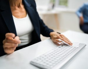 une femme nettoie son clavier d'ordinateur avec une lingette